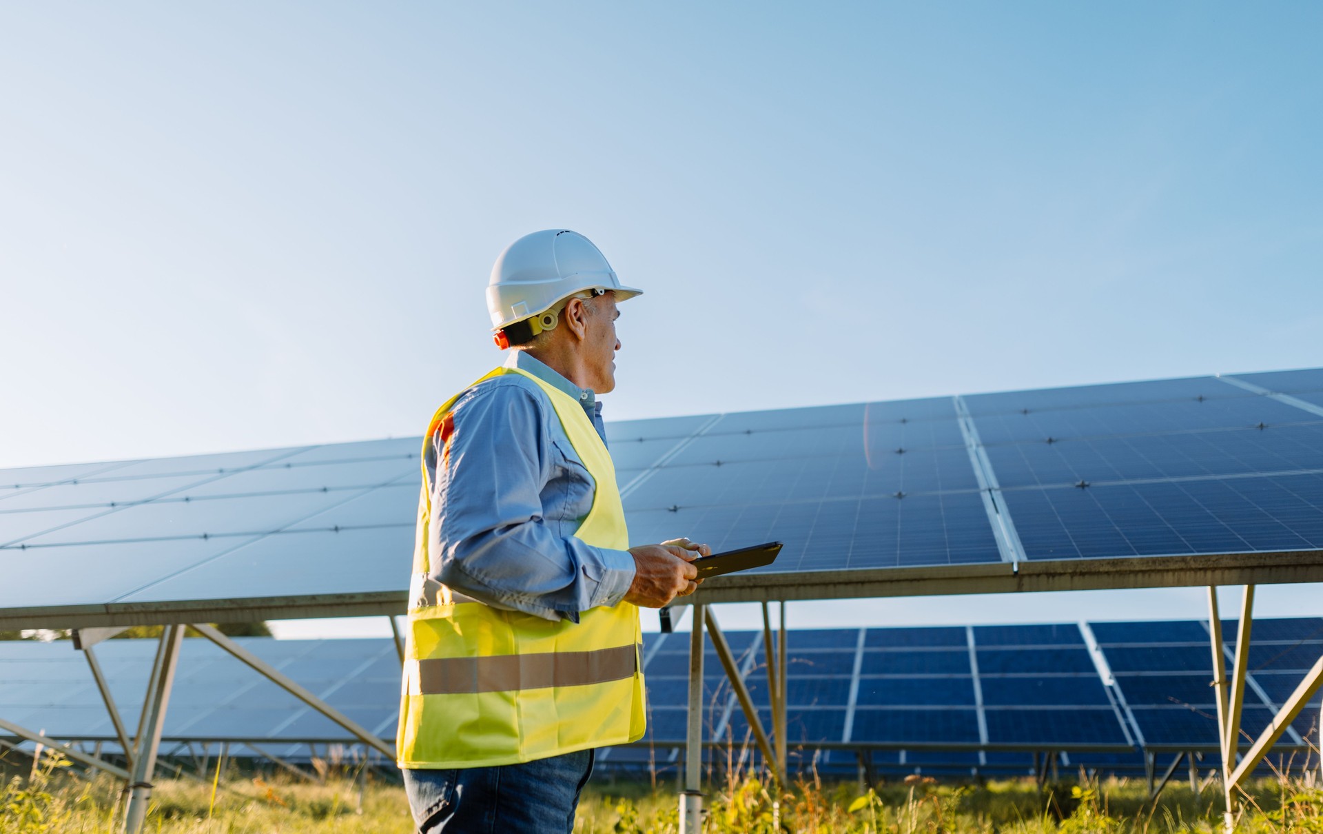 Worker checking solar panels with tablet in solar farm. Eco energy
